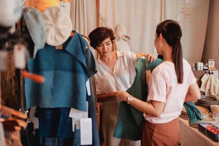 ผู้หญิงสองคนกำลังดูเสื้อผ้าด้วยกันภายในร้าน