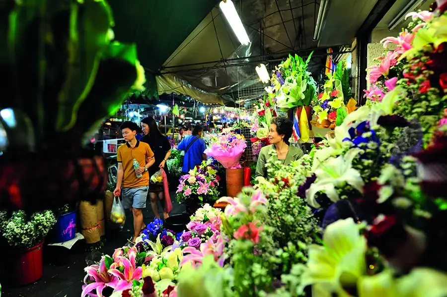 ผู้คนเดินเลือกซื้อดอกไม้ท่ามกลางร้านดอกไม้หลากสีที่ปากคลองตลาด กรุงเทพฯ