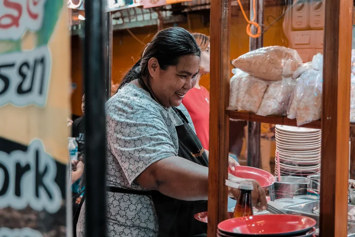 ผู้ประกอบการร้านอาหารกำลังทำงานและยิ้มอยู่หลังเคาน์เตอร์
