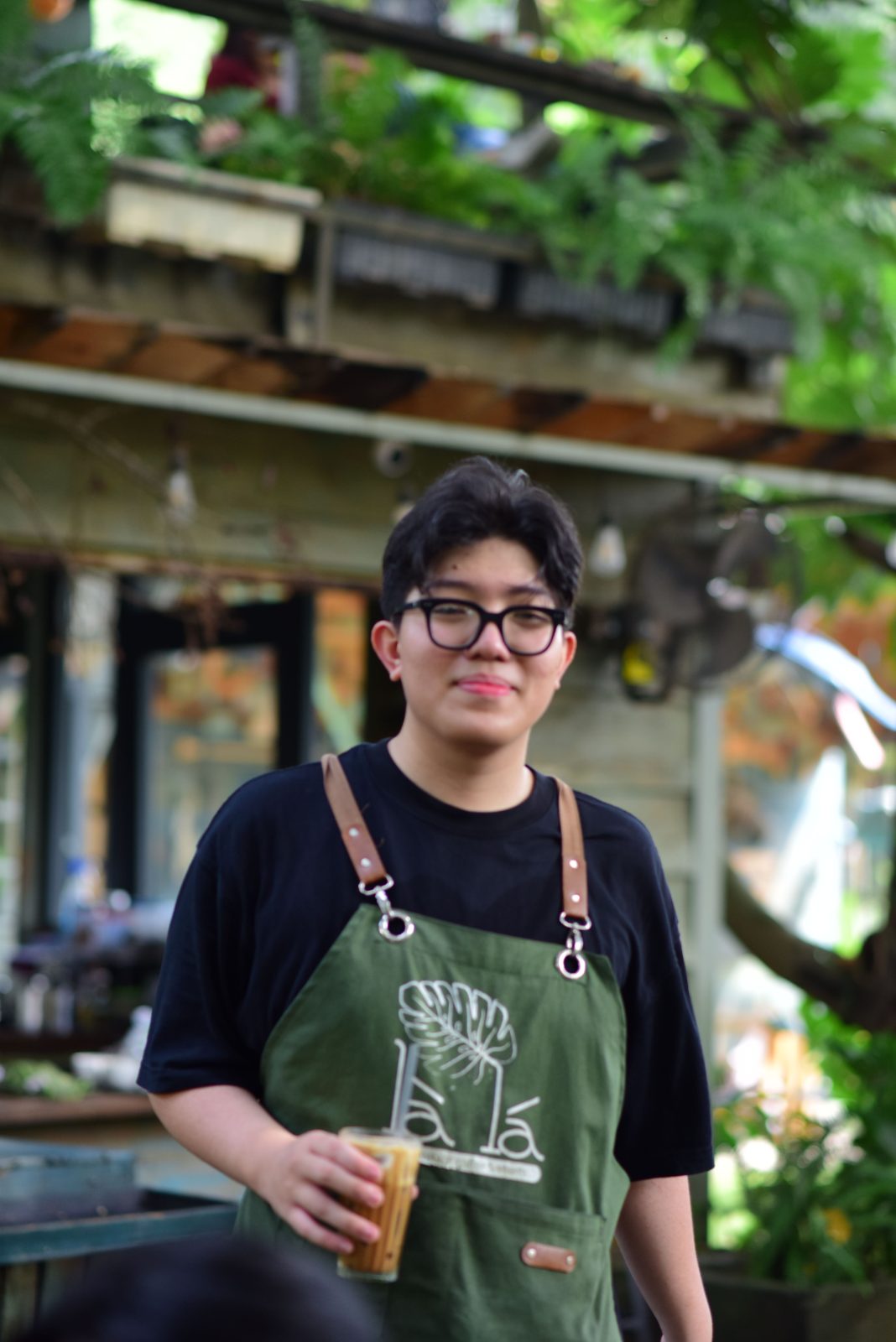 บาริสต้าหนุ่มยิ้มอยู่หลังเคาน์เตอร์คาเฟ่ที่เพิ่งเปิด
