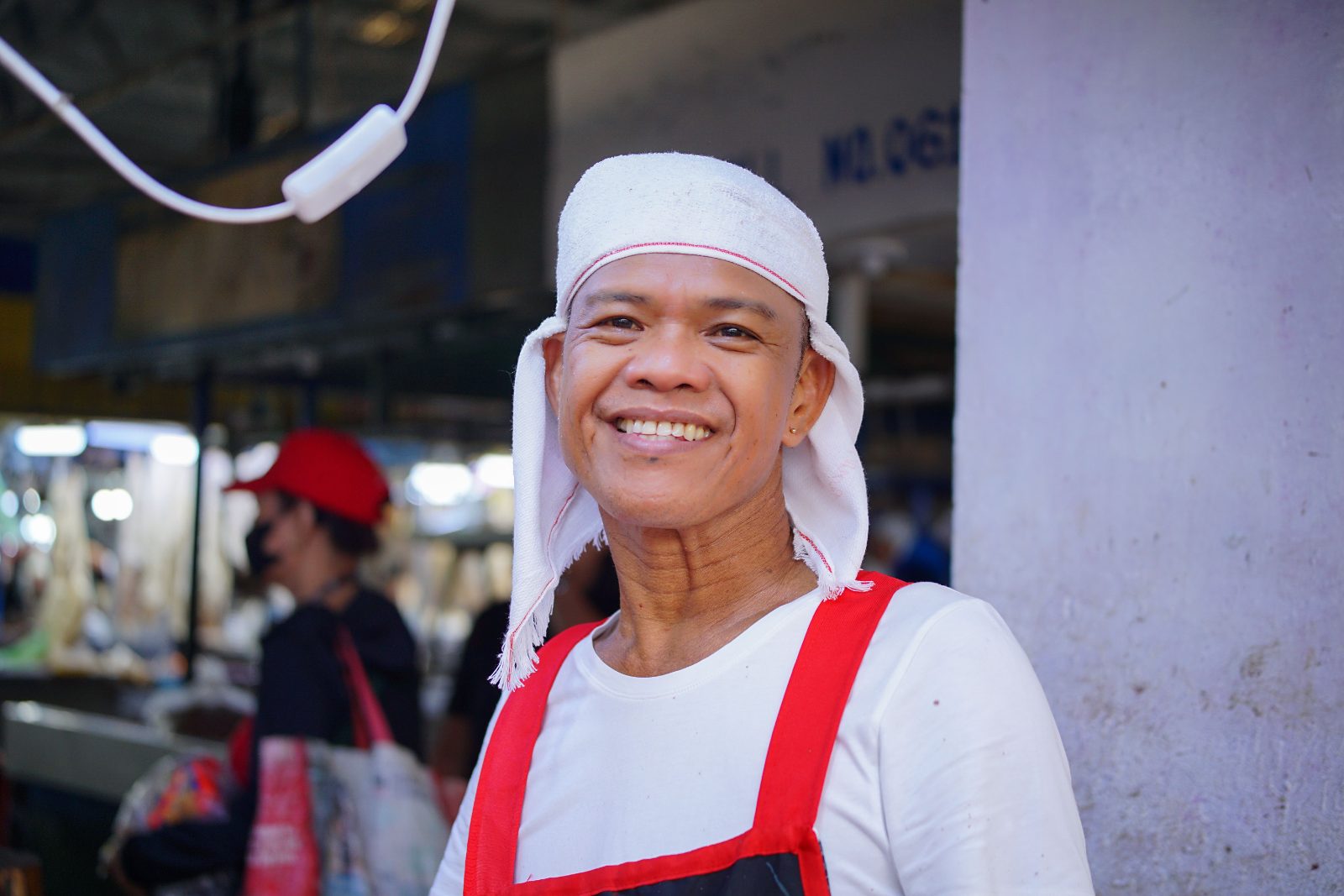 พ่อค้าสวมผ้าโพกหัวยิ้มกว้างอยู่หน้าร้านในตลาดสด